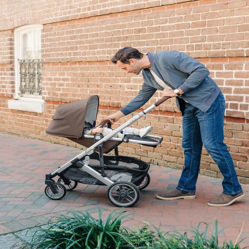 The new taupe stroller by uppababy. Father is leaning to check-in on baby in the stroller.