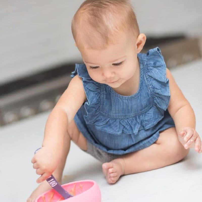 A baby enjoying a snack from her bowl that says, "Hello food I love you" by Bella Tunno.