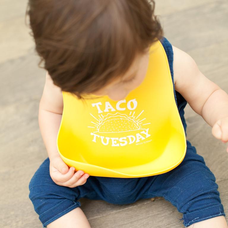A toddler wearing Bella Tunno's Wonder Bib that says, "Taco Tuesday"
