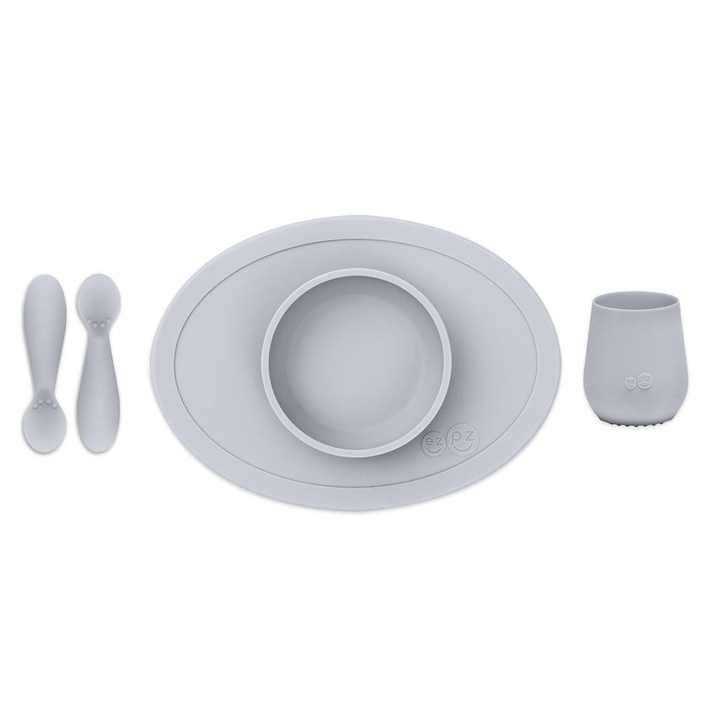 ezpz first food set in pewter grey includes 2 silicone spoons, a silicone bowl, and a silicone cup