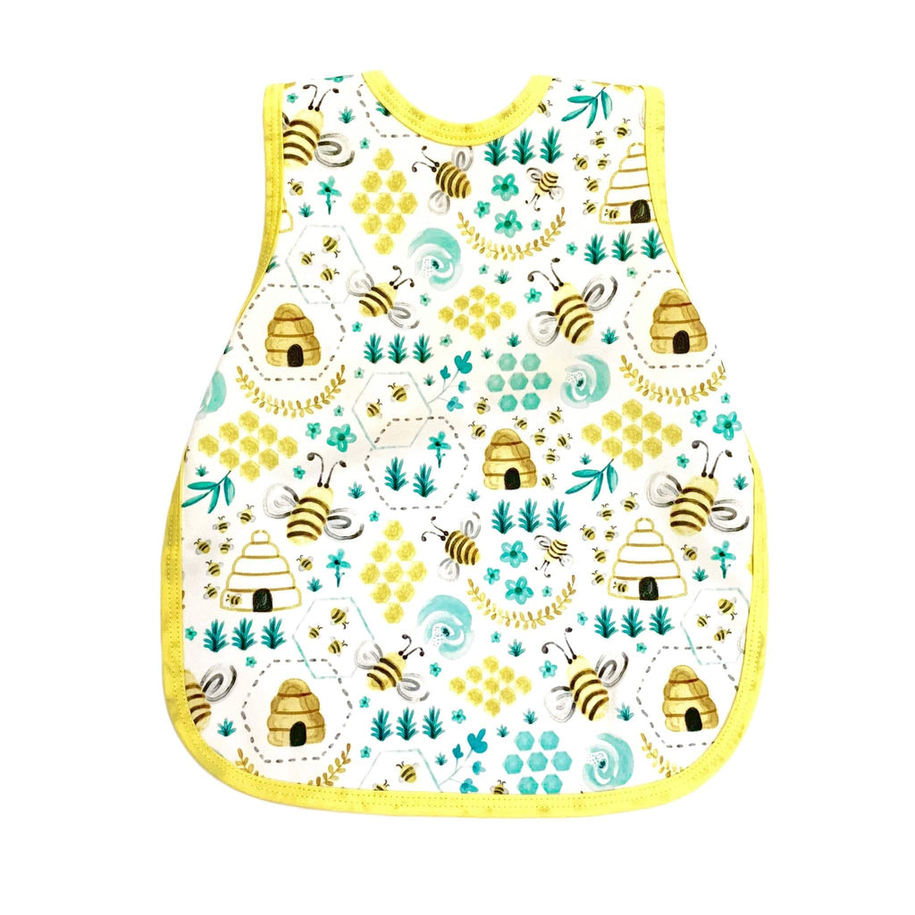 Bapron- bib apron is a hybrid between the two. It is full coverage and ties in the back. This one has yellow trim and bees and honey hives on it.