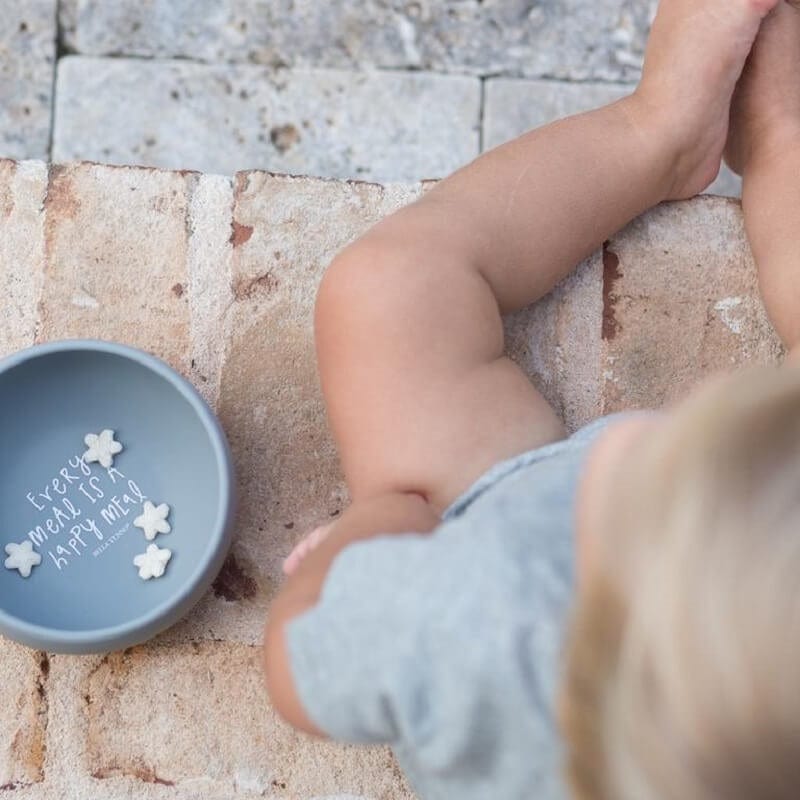 A little kid sitting with his bowl by Bella Tunno.