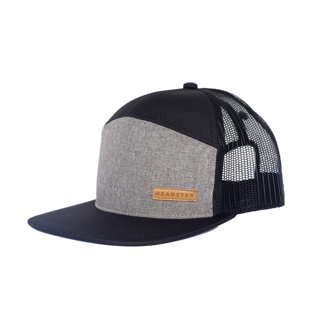 Headster's City Grey Ball Cap has a mesh back, with the front of the cap being black and grey. Headster's square light brown logo is on the front on one side and the brim is black.